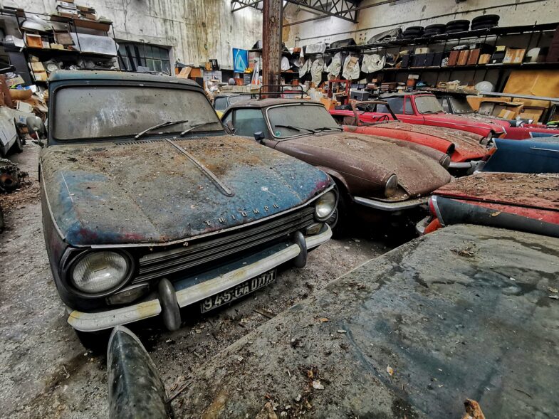 An abandoned garage with around a hundred Triumph cars